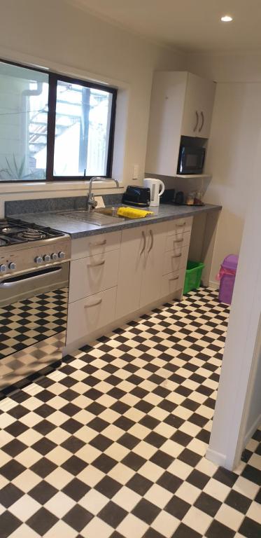 a kitchen with a black and white checkered floor at Lazy Daze at Athenree in Waihi Beach