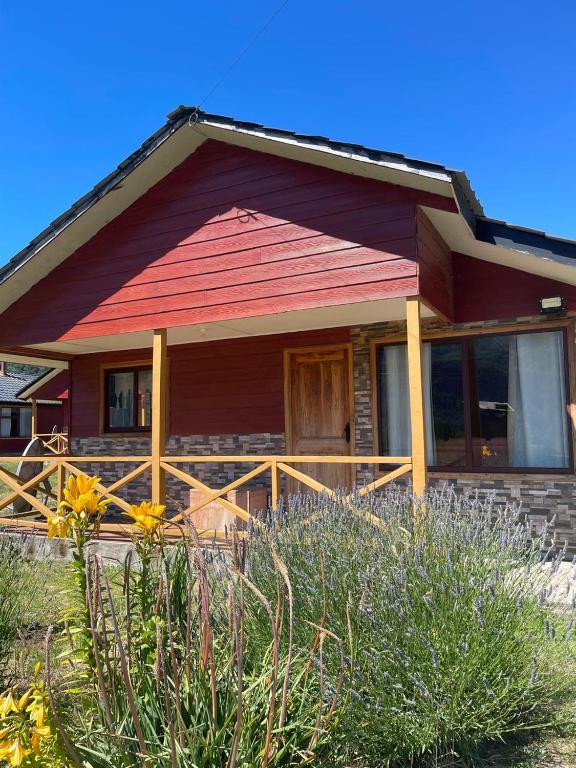 a home with a red roof and a wooden porch at Cabañas Valles del Mañihuales in Villa Maniguales