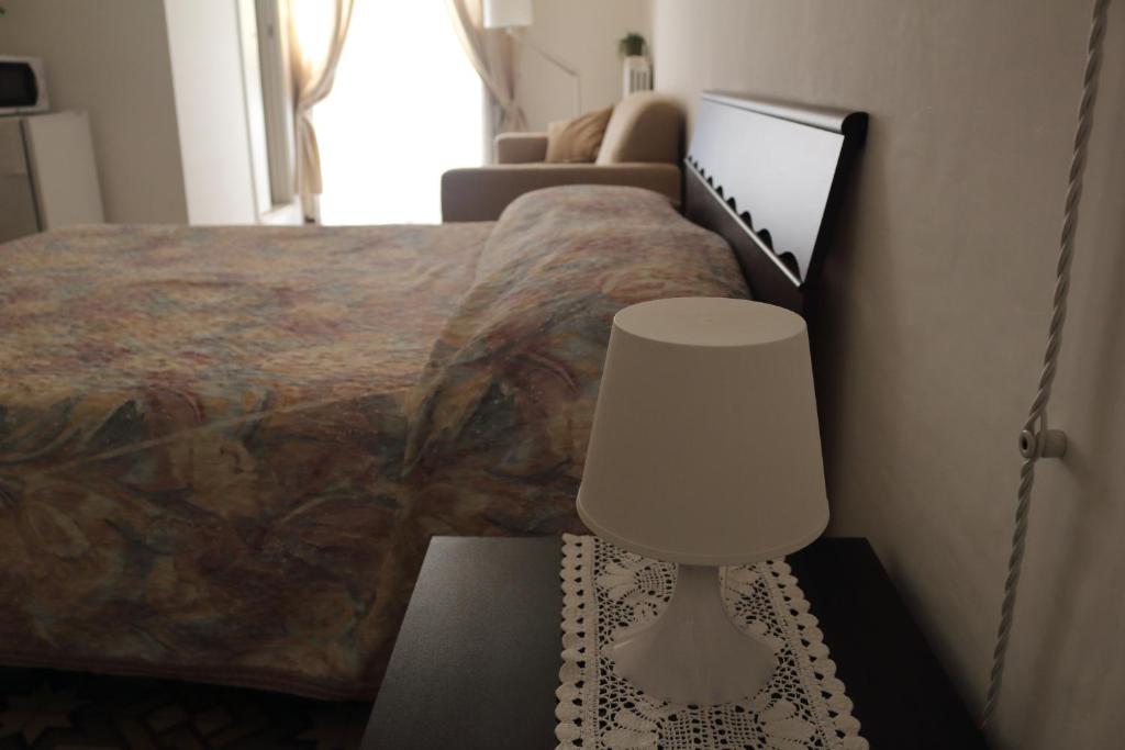 een slaapkamer met een bed en een tafel met een lamp bij B&B Huit in Martina Franca