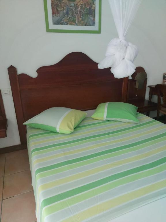 a bed with two green pillows and a lamp on it at Studios Soleil du Sud in Sainte-Anne