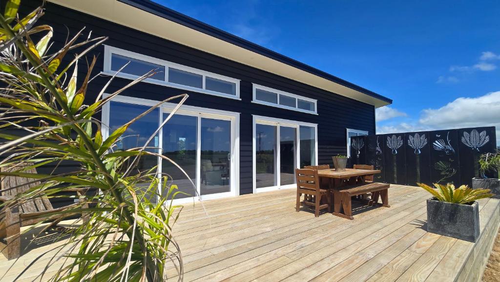 a wooden deck with a table and a house at The Quiet Paddock in Kairanga