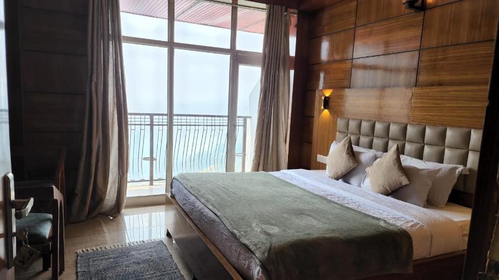 a bedroom with a bed and a large window at Hotel Mountain Nest in Nārkanda
