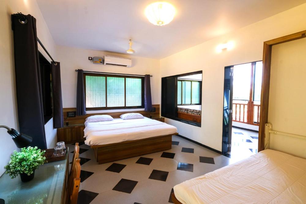 a bedroom with two beds and two windows at Saguna Baug Agro Tourism in Neral