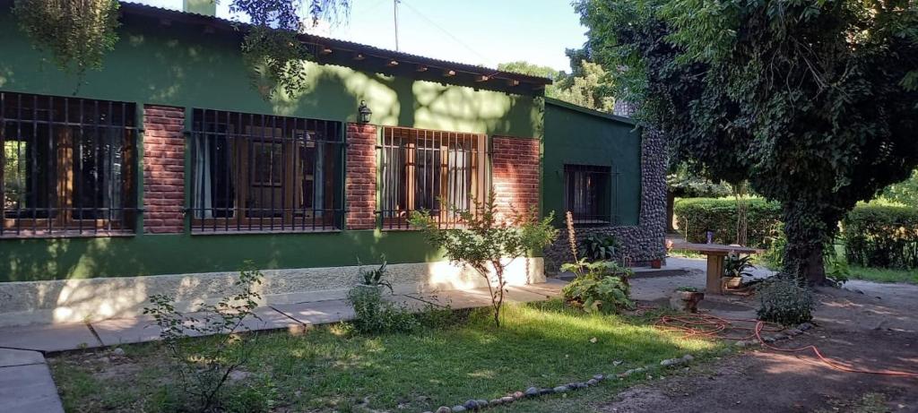 a green house with a bench in front of it at La Guevarina- Casa de Campo in Tres Esquinas