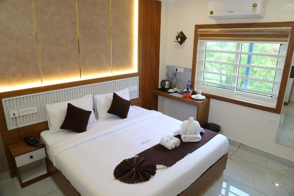 a bedroom with a large white bed with towels on it at Cloud9 Airport Hotel in Nedumbassery