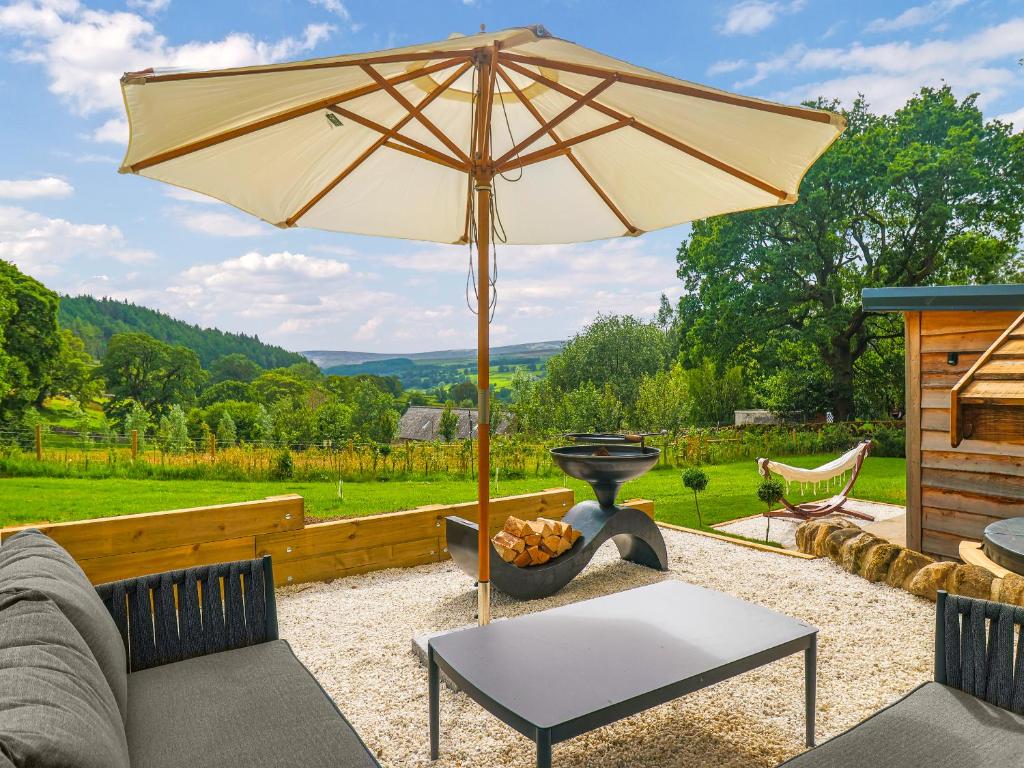 a patio with a table and an umbrella at The Twitcher - Uk50612 in Sabden