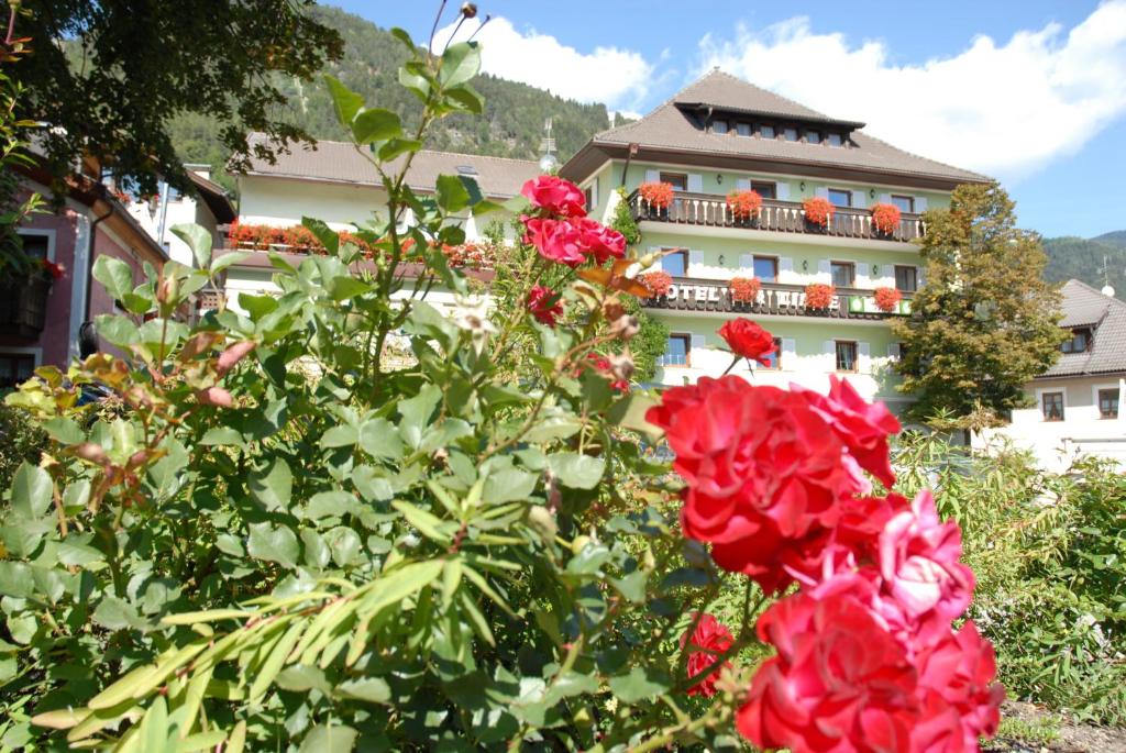 un edificio con rosas rojas delante de él en Hotel Gasthof Zur Linde, en Rio di Pusteria
