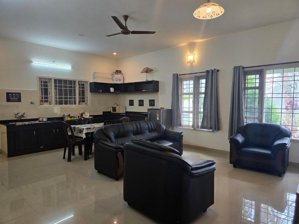 a living room with leather furniture and a kitchen at Guru Villa in Yercaud