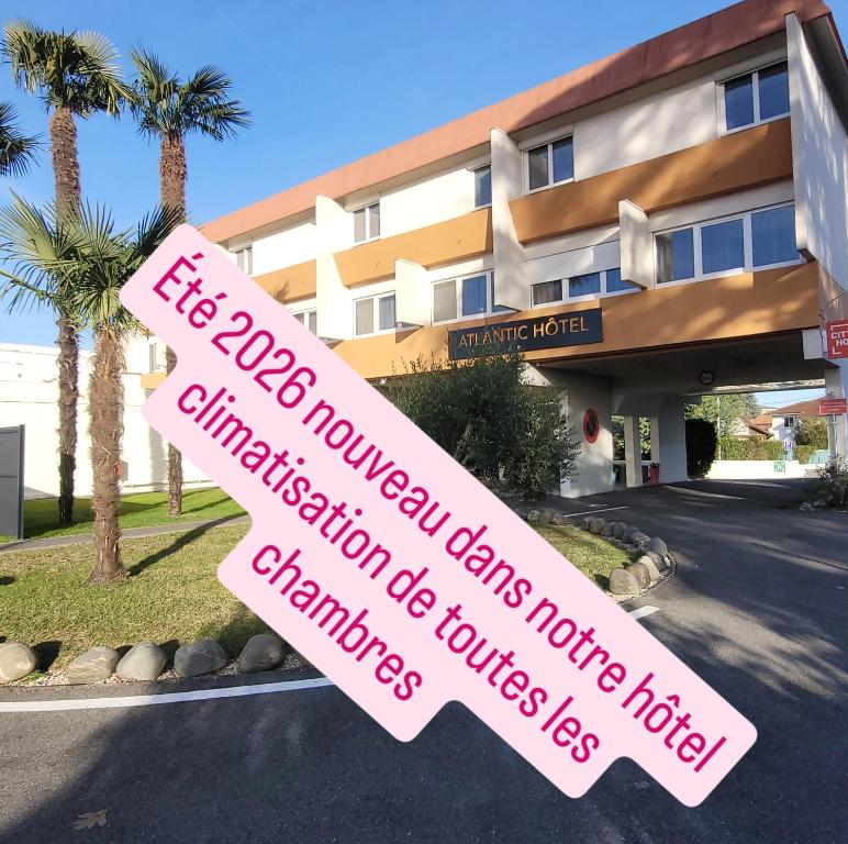 un cartello davanti a un edificio con palme di Atlantic Hôtel a Pau