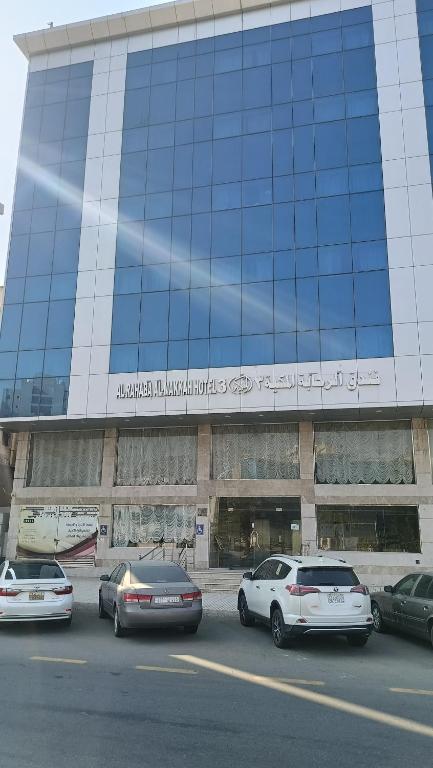 a large building with cars parked in front of it at الرحابة المكية الفندقية in Al Masfalah