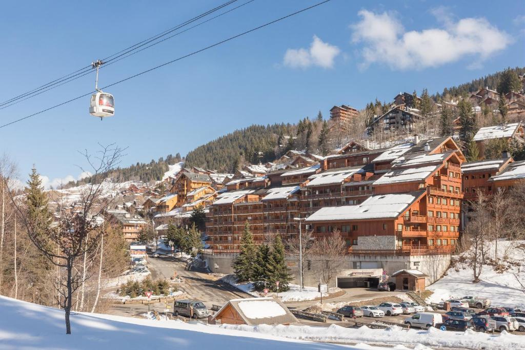 a ski lodge on a snowy mountain with a ski lift at Residence Les Ravines - maeva Home in Méribel