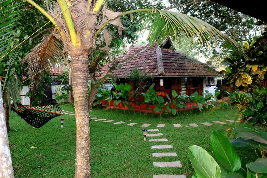 a small house with a palm tree in front of it at Ayurprana Marari in Mararikulam