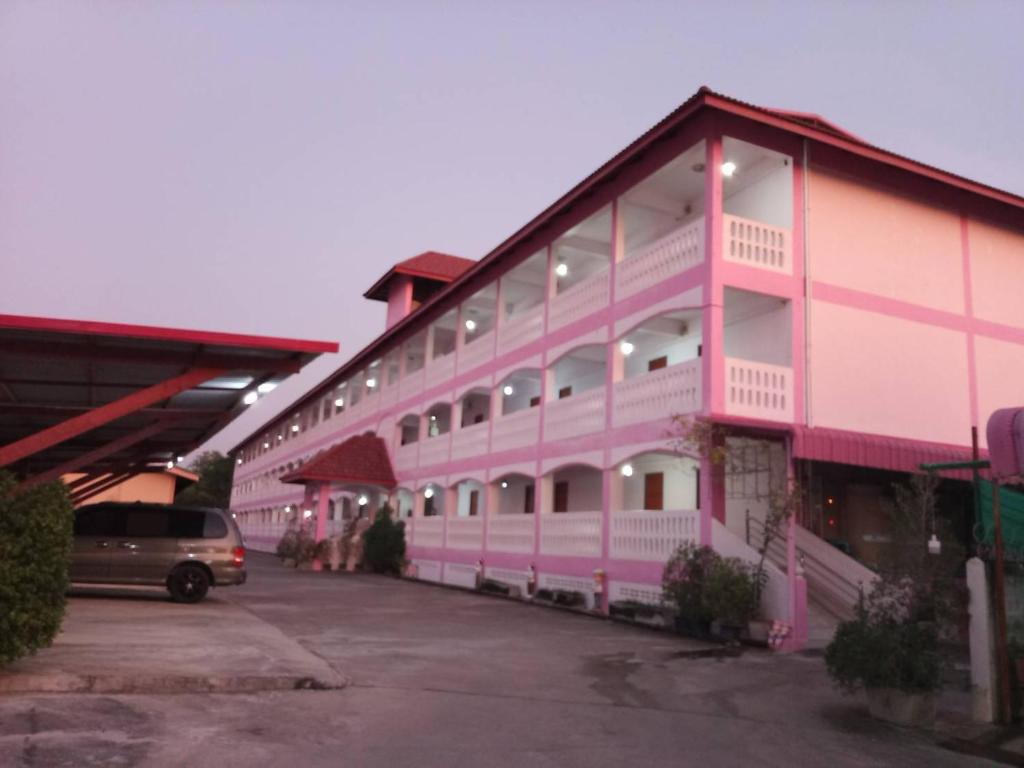 a pink building with a car parked in a parking lot at ลพบุรีทาวน์ Lopburi Town in Lop Buri