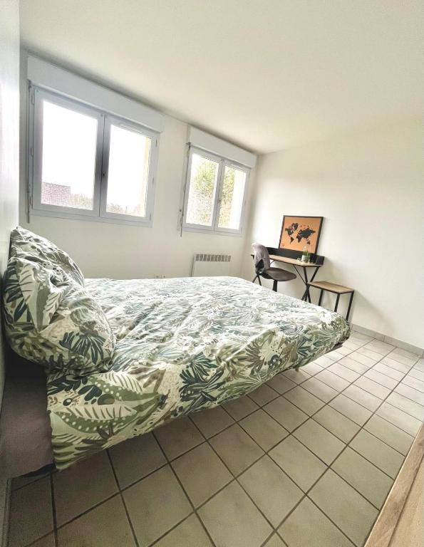 a bedroom with a bed with a green and white bedspread at Studio Cosy proche CHU in Amiens