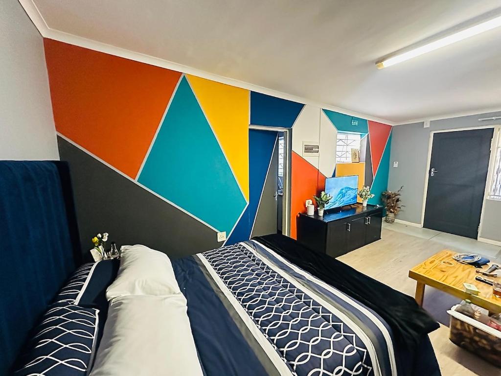 a bedroom with a colorful wall with a bed at AAA Luxury Cottages in Cape Town