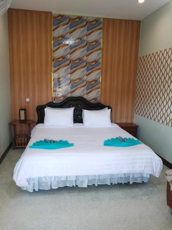 a bedroom with a large white bed with blue pillows at บ้านพัก สายรุ้ง in Ban Hua Saphan
