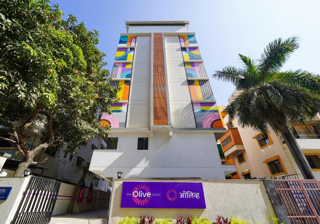 a tall building with a purple sign in front of it at Olive Hotel Wakad by Embassy Group in Pune