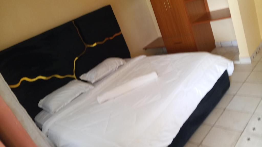 a large white bed with a black headboard in a room at palm ridge apartment Diani beach in Diani Beach