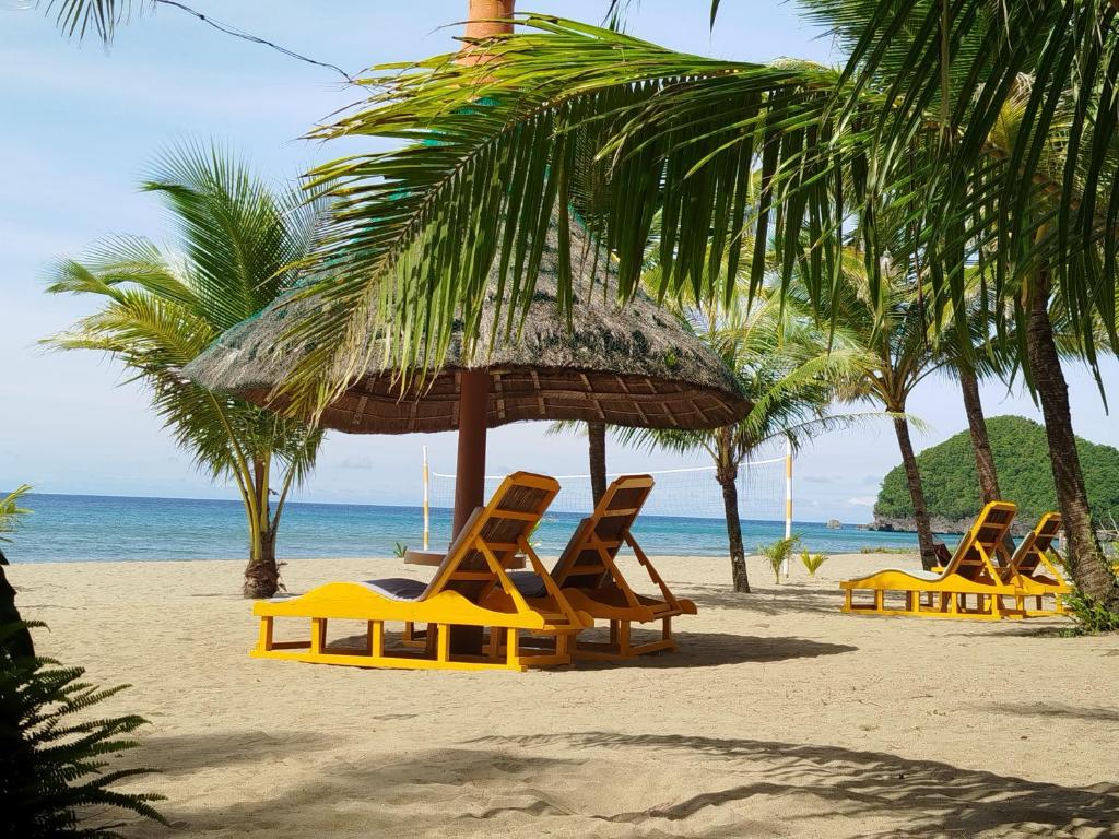 a group of lounge chairs and an umbrella on a beach at Bermuda Beach Resort in Lagob