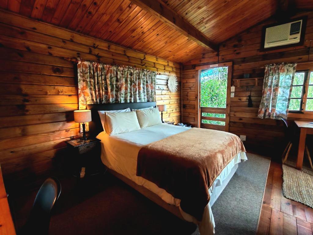 a bedroom with a bed in a log cabin at Tegwaan's Nest B&B in Mooiriver