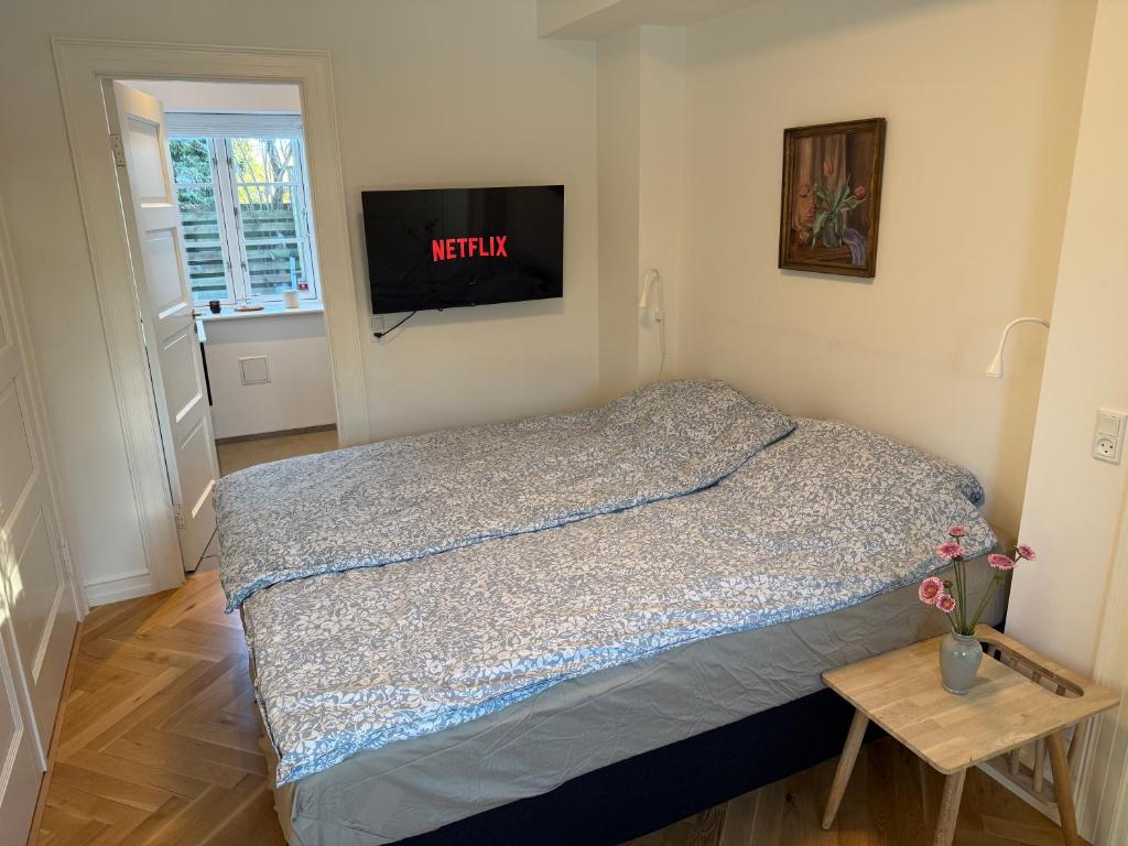 a bedroom with a bed with a television on the wall at Ny & hyggelig moderne suite in Hvidovre