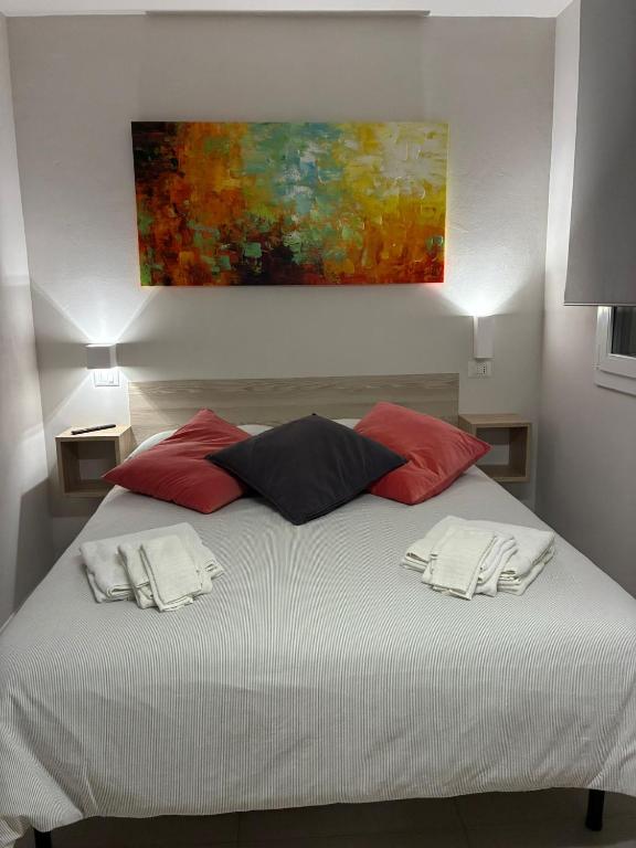 ein weißes Bett mit roten Kissen und ein Gemälde an der Wand in der Unterkunft Loft Mag in Fanano