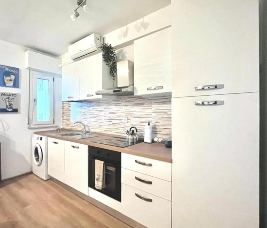a kitchen with white cabinets and a sink at JuliaHome in Marina Julia