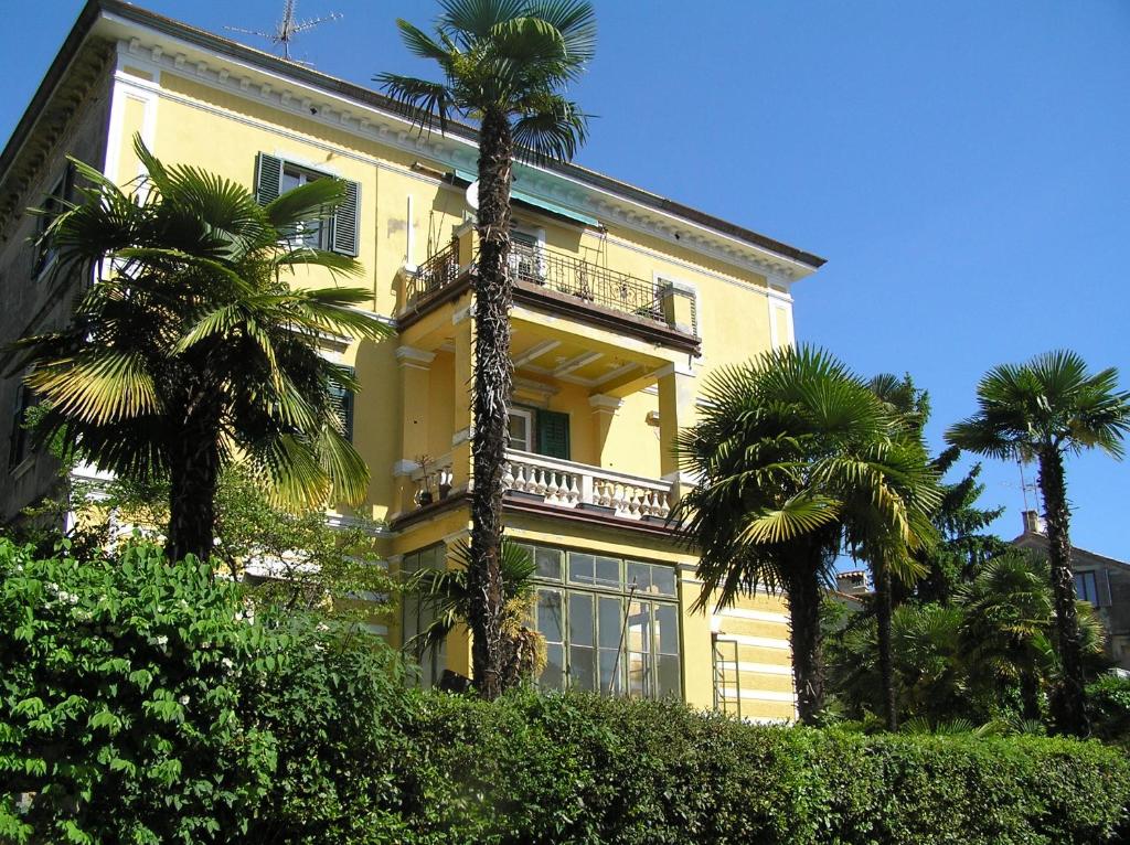 un edificio giallo con palme di fronte di Studio Villa Mir a Opatija