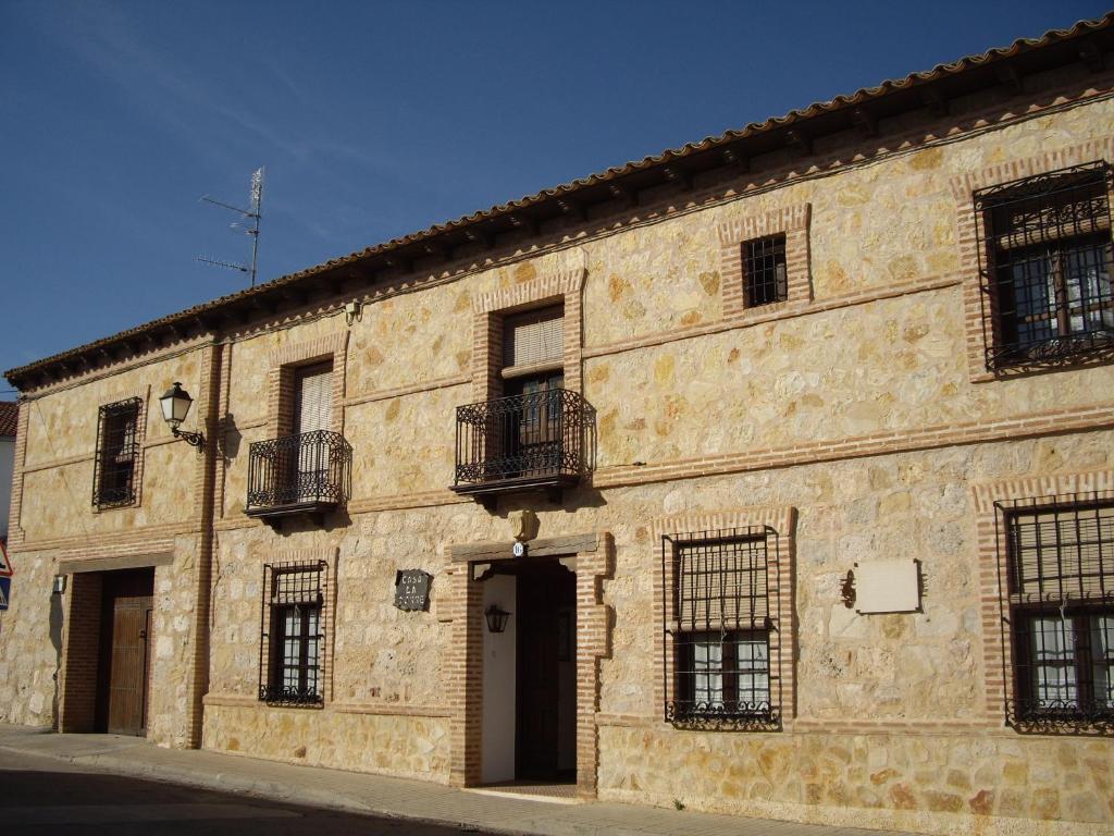 un antiguo edificio de piedra con ventanas y una puerta en Hospederia Casa de La Torre, en El Toboso