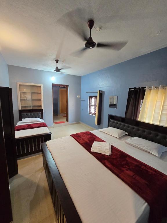 a bedroom with two beds and a ceiling fan at Ayodhya Home stay in Māvalli