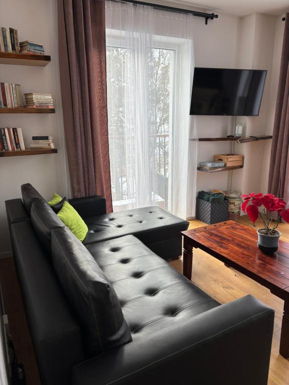 a living room with a black leather couch and a table at TatryForRest in Starý Smokovec