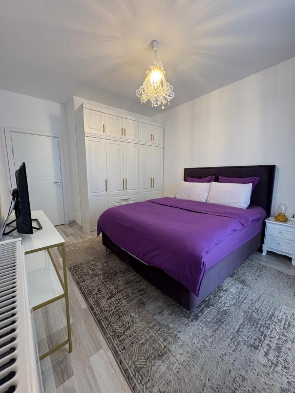 a bedroom with a purple bed and a chandelier at Safirului apartment in Bragadiru