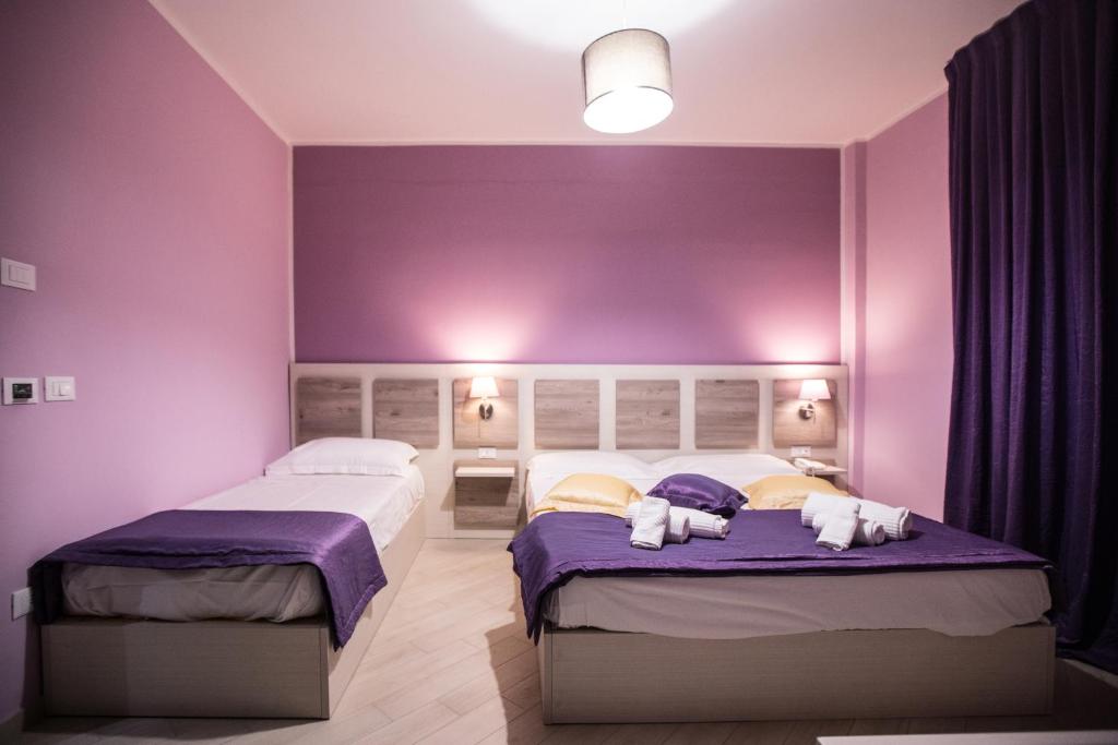 2 camas en una habitación con paredes moradas en Hotel Cliché, en San Lucido