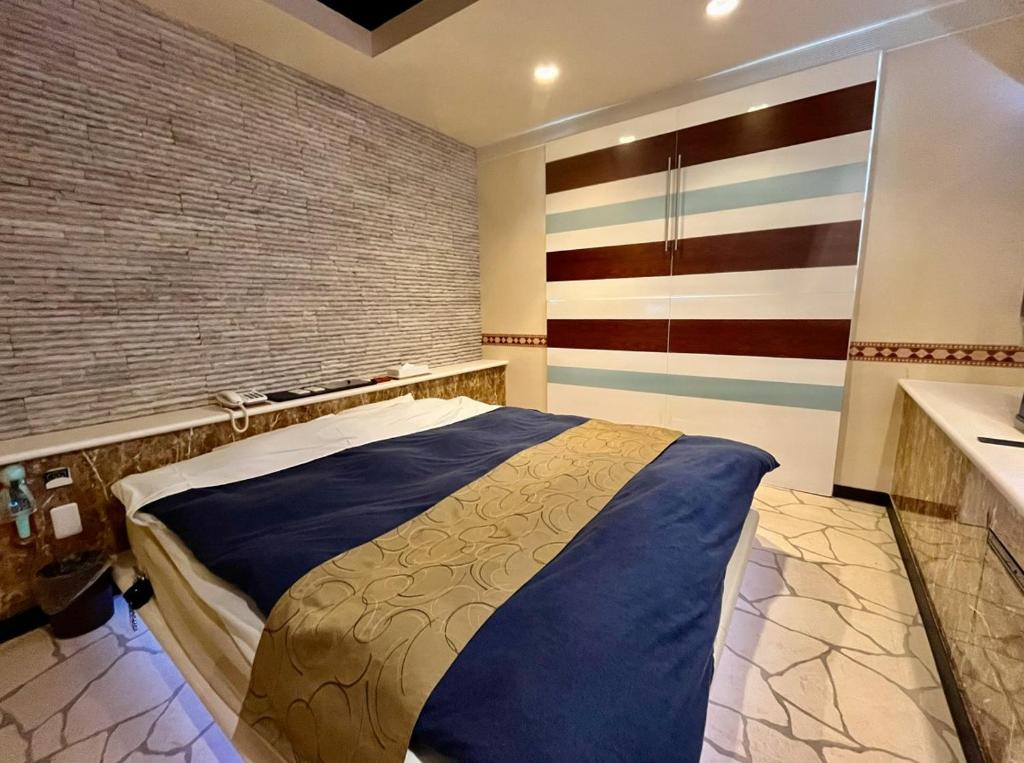 a bedroom with a large bed with a brick wall at ホテル アルファ in Iizaka