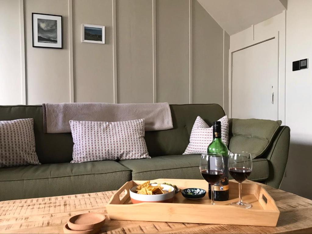 a green couch with a tray of food and wine glasses at Manderley Cottage, Mousehole in Mousehole