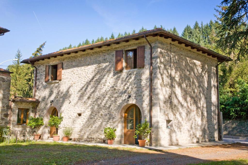 an old stone house with trees in the background at La Casetta di Giovanni in Pratovecchio