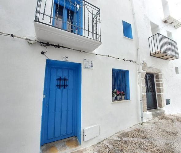 a blue door on a white building with a balcony at Casa el far Peñíscola in Peniscola