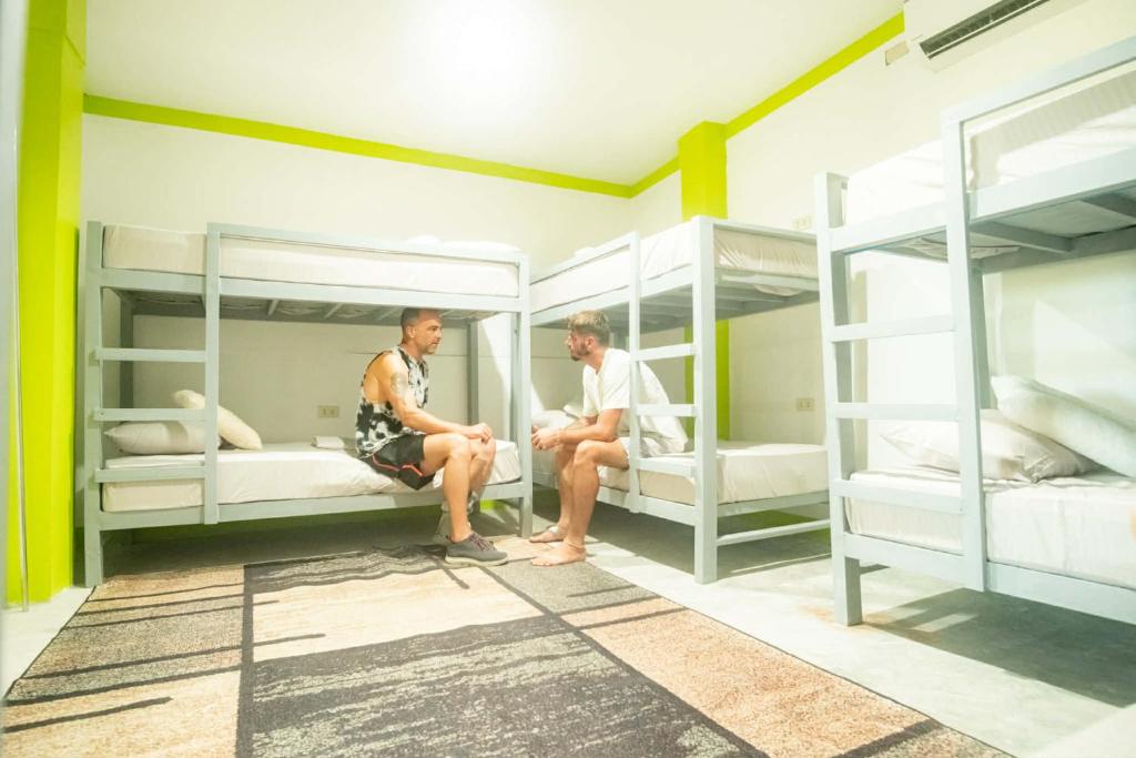 two men sitting in a room with bunk beds at Matropica CoWorking Hostel in General Luna
