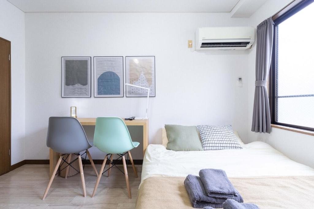 a bedroom with a bed and two chairs and a desk at Kunark KM102 Stay in Kokubunji