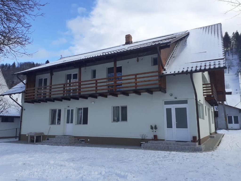 a house with a balcony on top of it in the snow at La Moieciu pe Deal in Moieciu de Jos