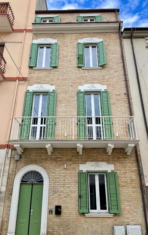a building with green shutters and a balcony at Affittacamere Casa Florens Guest House in San Benedetto del Tronto