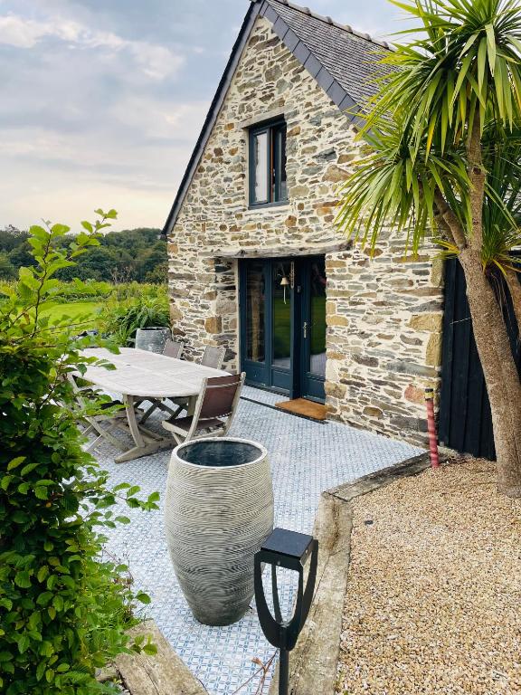 a stone cottage with a table and a palm tree at Dépendance chez l'habitant in Morlaix