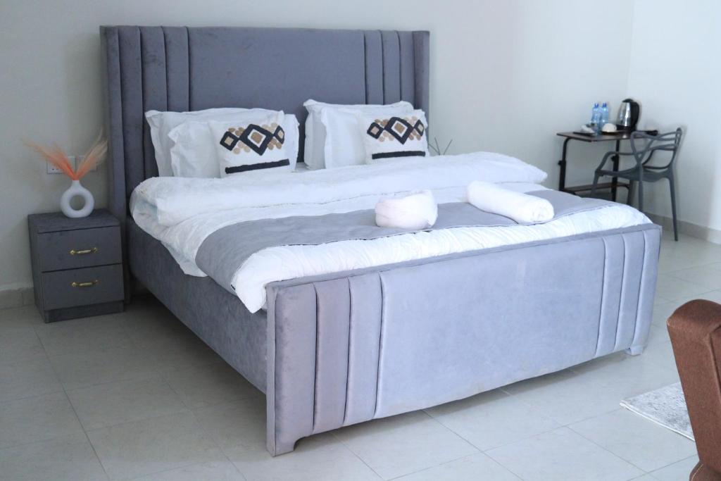 a bedroom with a large bed with white sheets and pillows at The Premier Comfort in Nairobi