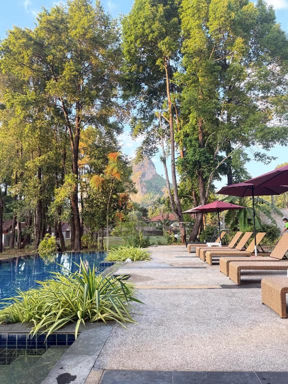a park with a pool and benches and trees at Green Haven Villas in Krabi