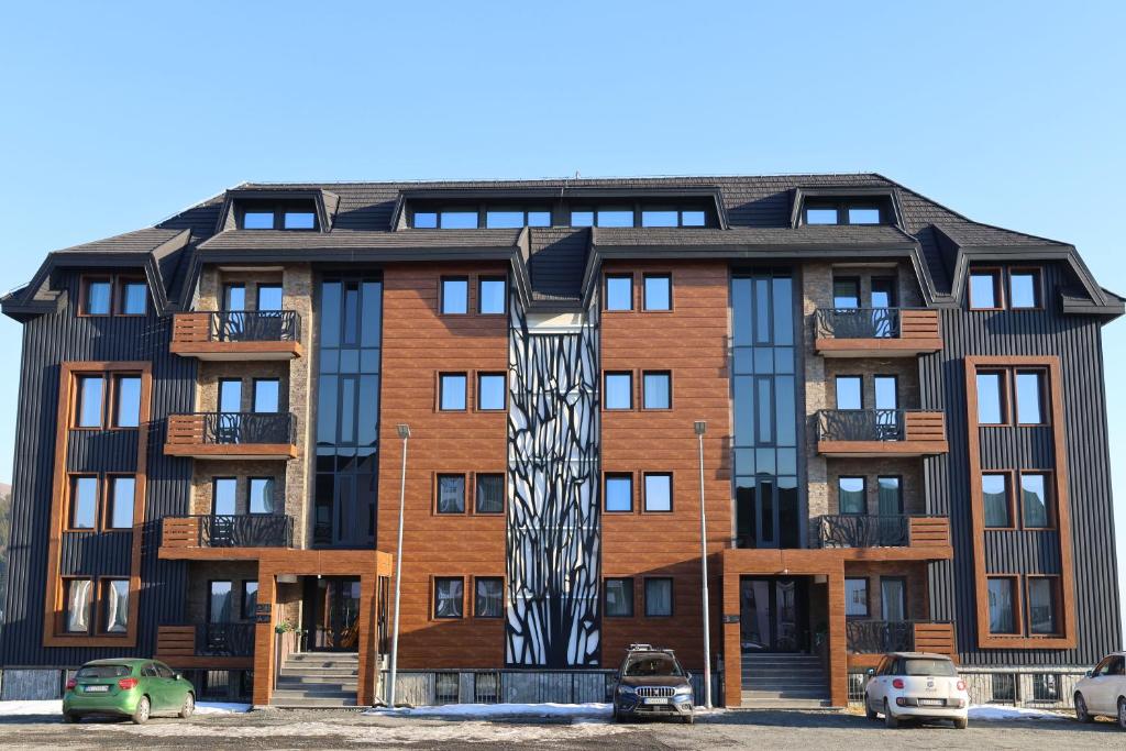an apartment building with a sculpture in front of it at Mountain Paradise Ski In & Out - Vila Golija Kopaonik in Kopaonik