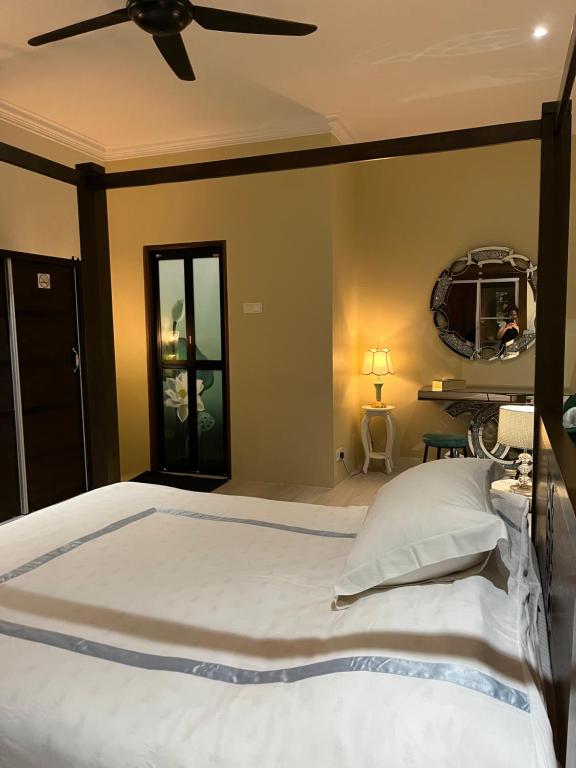 a bedroom with a large bed with a ceiling fan at Summerland Seaside Villa in Kampong Telaga Papan