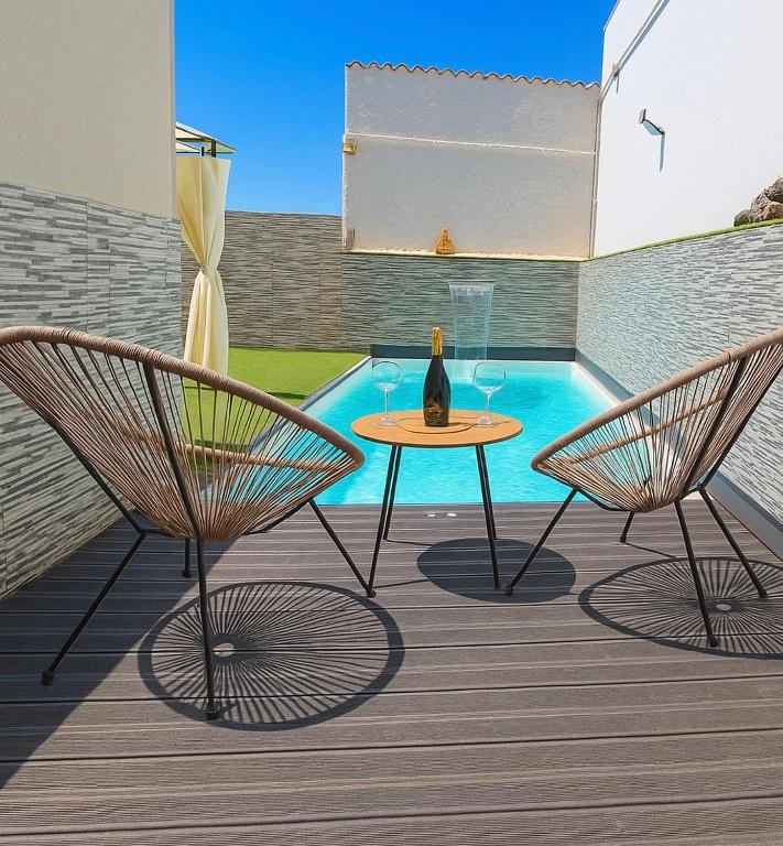a patio with two chairs and a table with a bottle of wine at Pablo House Beach in Telde