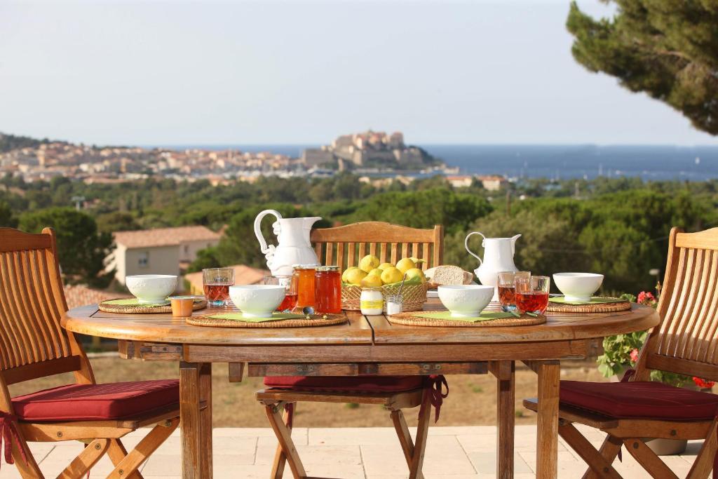 a wooden table with food on it with two chairs at La Ghisonaise Maison d'hôtes in Calvi