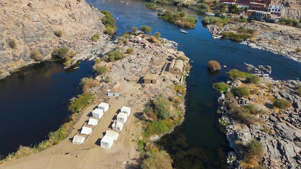 an aerial view of a river with a group of buildings at ASSINGAR camp in Jazīrat Suhayl
