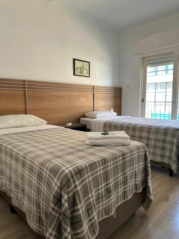 zwei Betten in einem Hotelzimmer mit karierter Bettwäsche in der Unterkunft Veneto Hotel in Canguçu